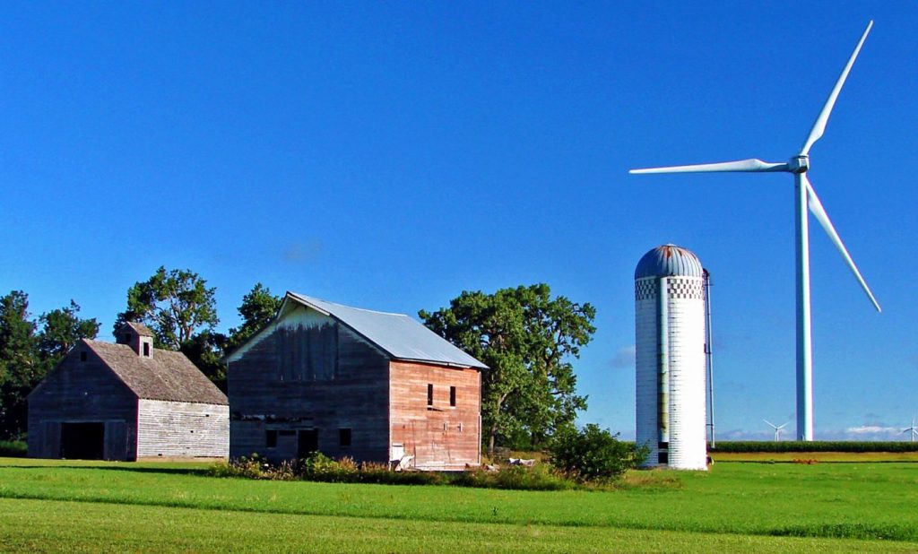 Wind turbines on green hills under a wide sky, symbolising climate action.